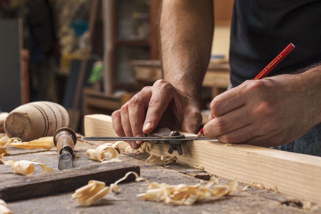 Carpintero de Astorga midiendo a mano una pieza de madera en el taller